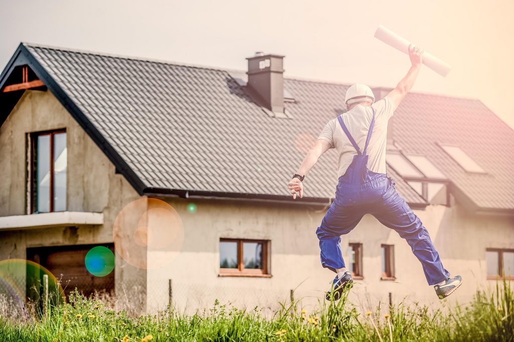 man in work gear doing a jump shot on a green lawn